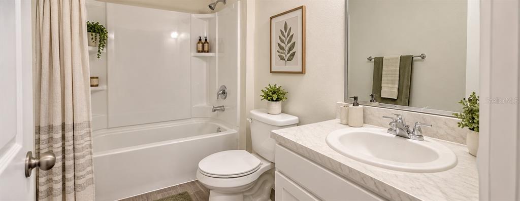A bathroom features a white vanity with a marble-look countertop, a toilet, and a tub-shower — 53 ORCHID COURT, POINCIANA, FL