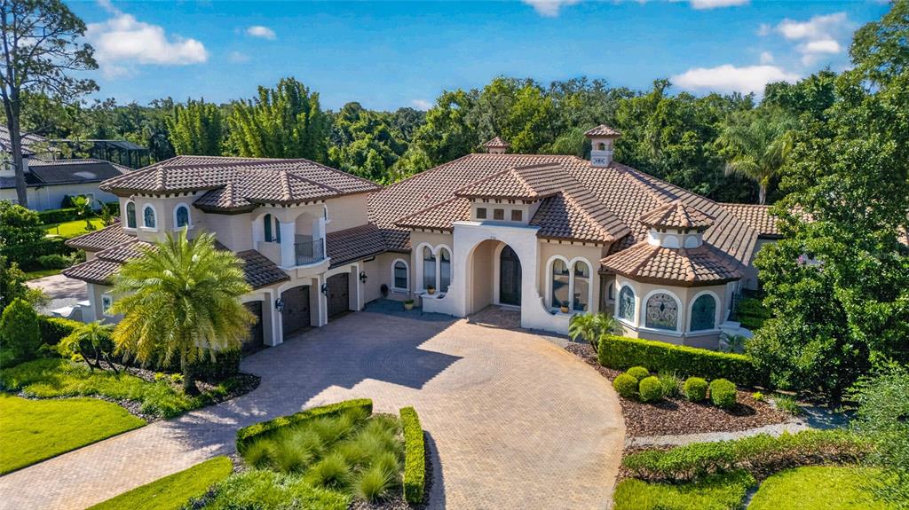 An aerial view of a large Mediterranean-style house with a tile roof and paved driveway — 7765 ISLEWOOD COURT, SANFORD, FL