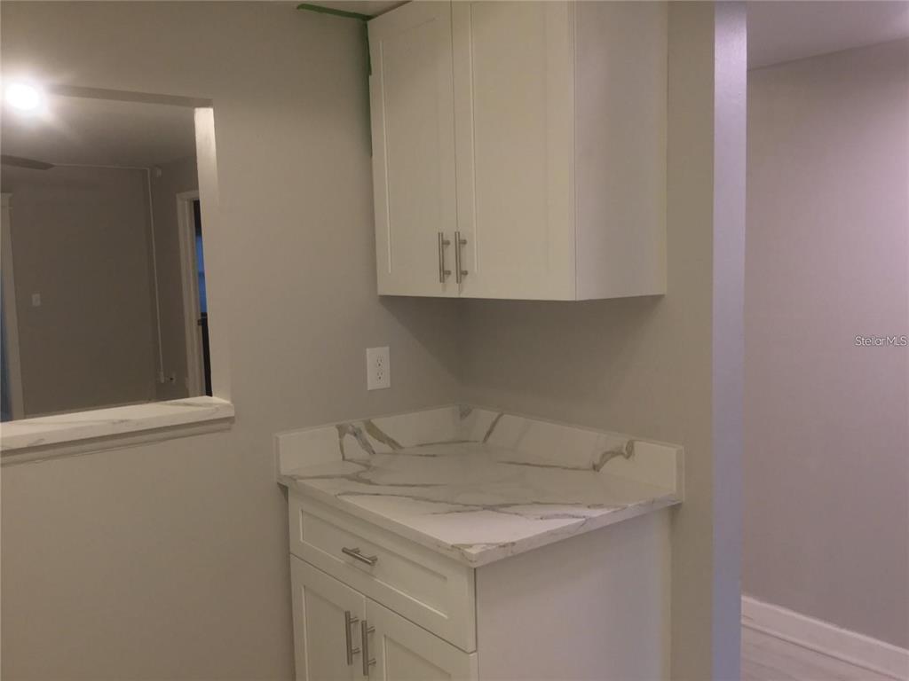 A kitchen area features white cabinets, a marble-patterned countertop, and a pass-through window — 1100 E BAY DRIVE UNIT 82, LARGO, FL