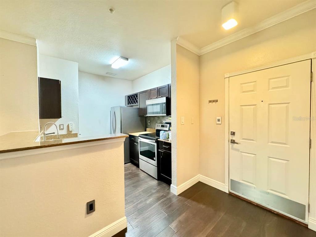 This view shows a kitchen with dark cabinets and stainless steel appliances near an entryway — 5000 CULBREATH KEY WAY UNIT 1-318, TAMPA, FL