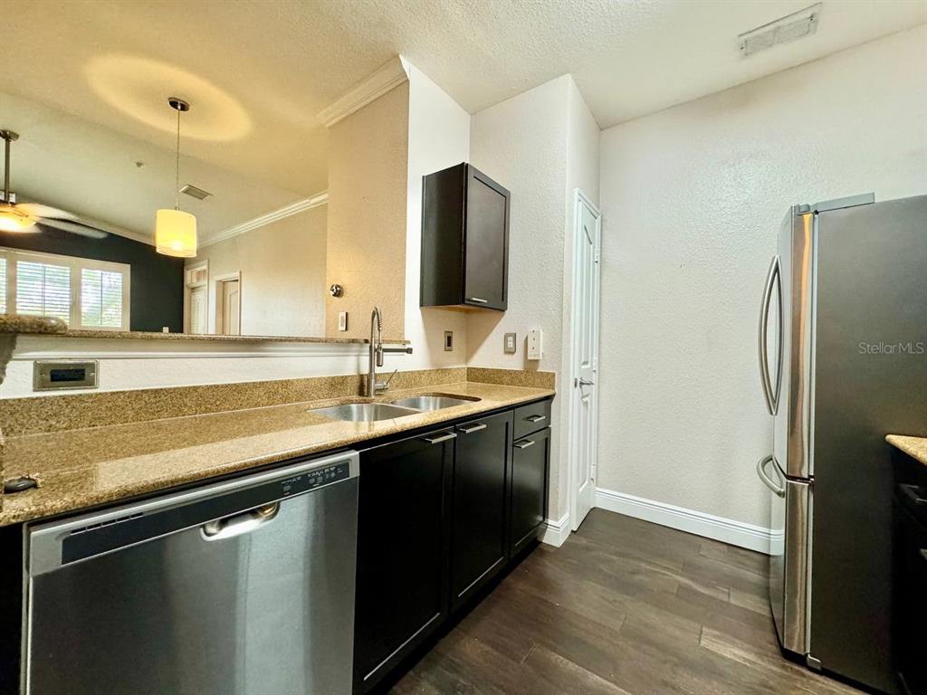 A kitchen features dark cabinets, granite countertops, stainless steel appliances, and wood-look flooring — 5000 CULBREATH KEY WAY UNIT 1-318, TAMPA, FL