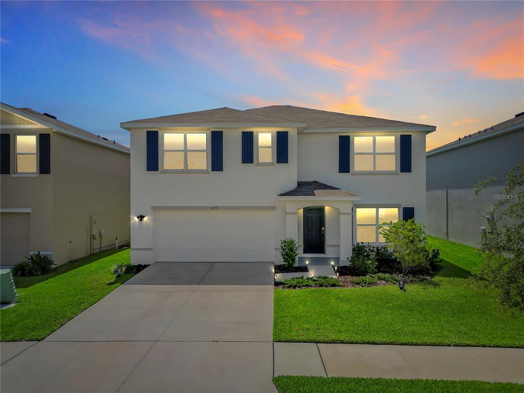 A two-story suburban house with a white exterior, dark shutters, and a two-car garage — 16531 WINDMILL FORGE PASS, WIMAUMA, FL
