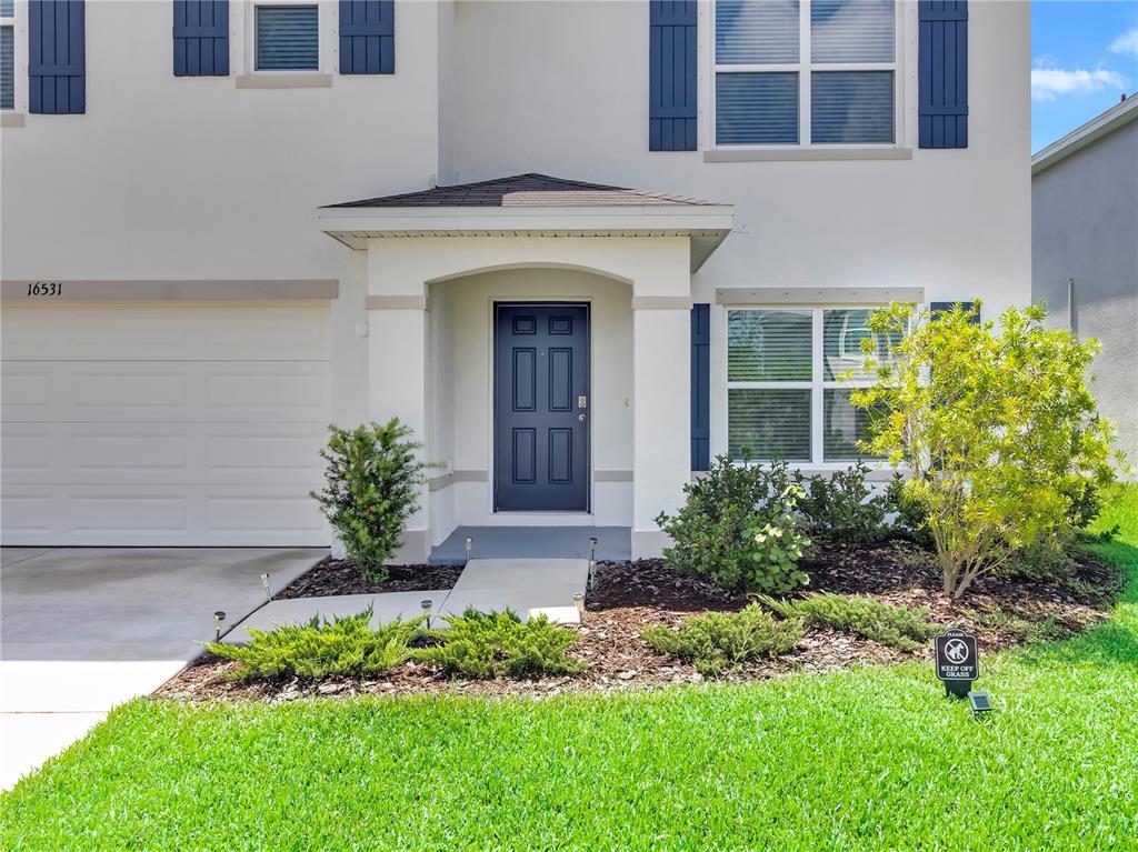 The exterior of a two-story house features a dark blue front door and window shutters — 16531 WINDMILL FORGE PASS, WIMAUMA, FL