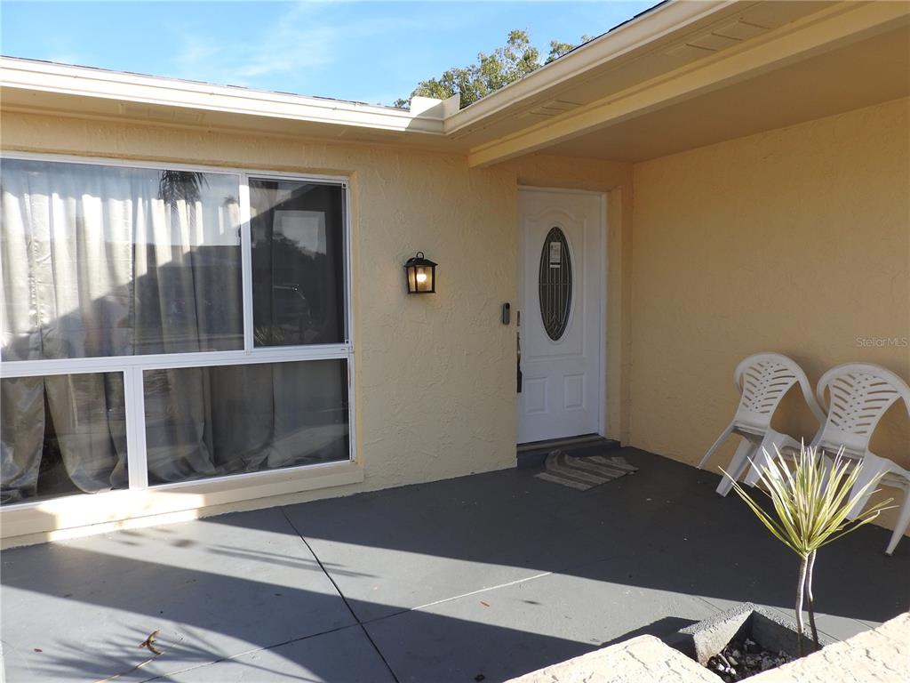 A front porch with a white door, a large window, and two white plastic chairs — 1324 VIKING DRIVE, HOLIDAY, FL