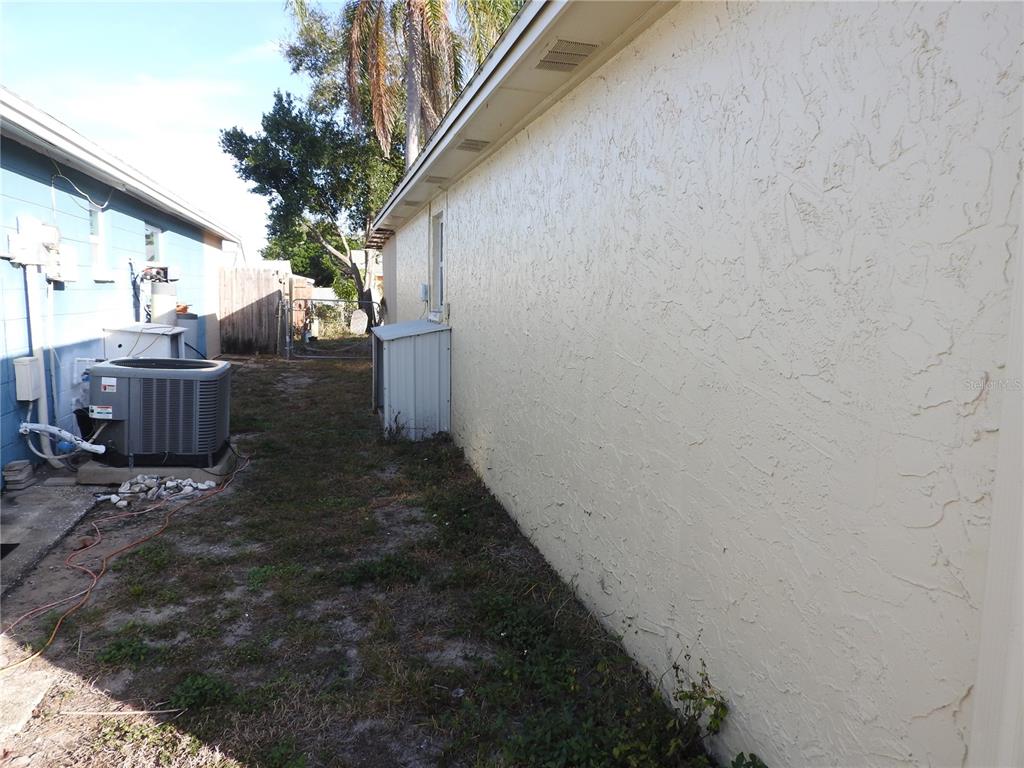A side view of a house exterior with a stucco wall and an air conditioning unit — 1324 VIKING DRIVE, HOLIDAY, FL