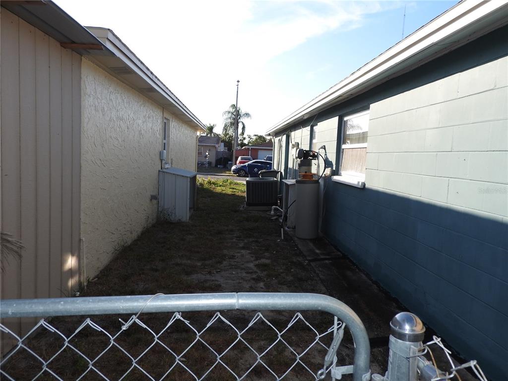 A narrow outdoor side yard between two houses with a chain-link fence in the foreground — 1324 VIKING DRIVE, HOLIDAY, FL