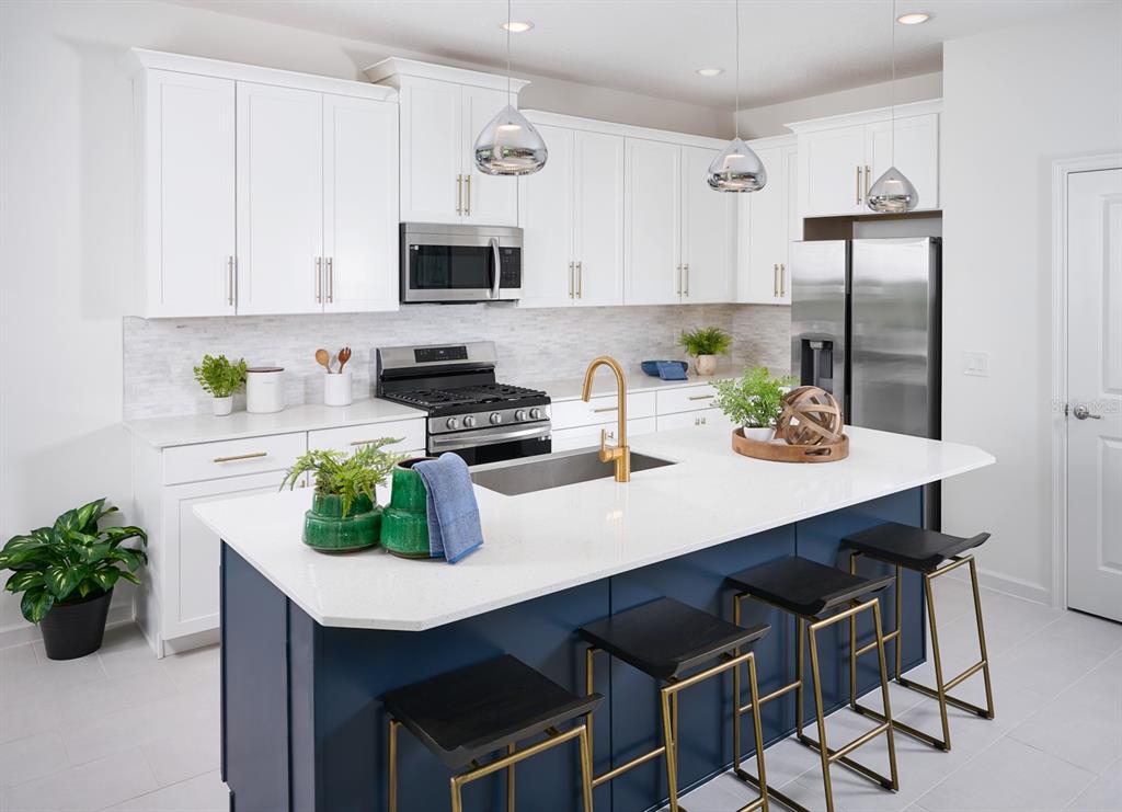 A modern kitchen features white cabinets, a navy blue island, and stainless steel appliances — 2248 SIRENA LANE, MOUNT DORA, FL
