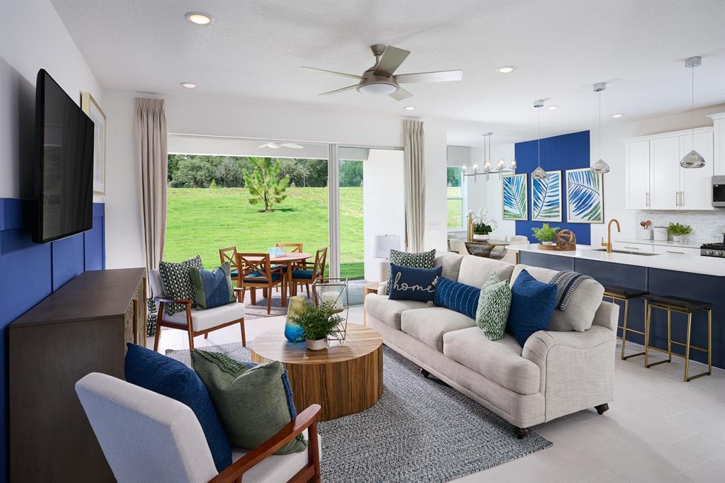 An open-concept living room and kitchen featuring a beige sofa, blue accents, and sliding doors — 2248 SIRENA LANE, MOUNT DORA, FL