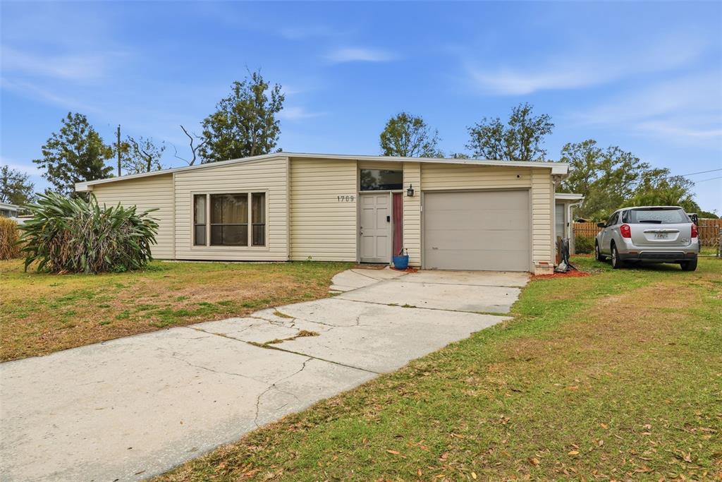 A single-story house with beige siding, a garage, and a concrete driveway — 1709 CARNEGIE CIRCLE, TAMPA, FL