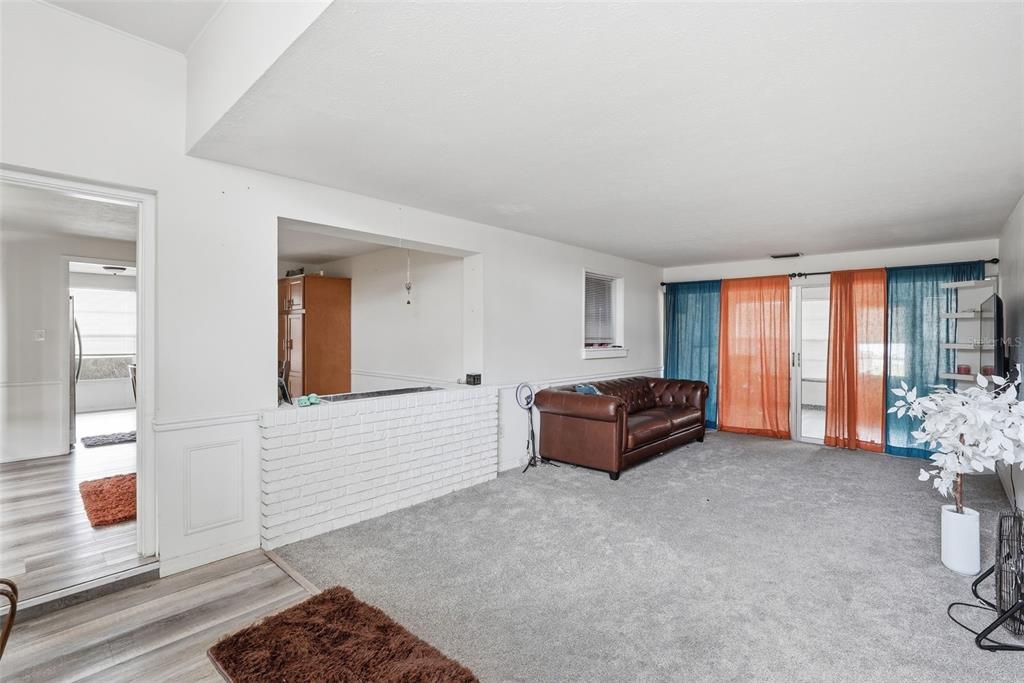 A living room with gray carpet, a brown leather sofa, and a white brick partition — 1709 CARNEGIE CIRCLE, TAMPA, FL