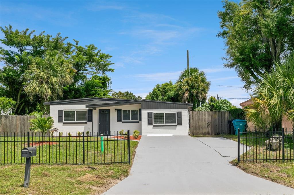 A single-story white house with a dark roof, front door, and a concrete driveway — 2821 W AMELIA STREET, ORLANDO, FL