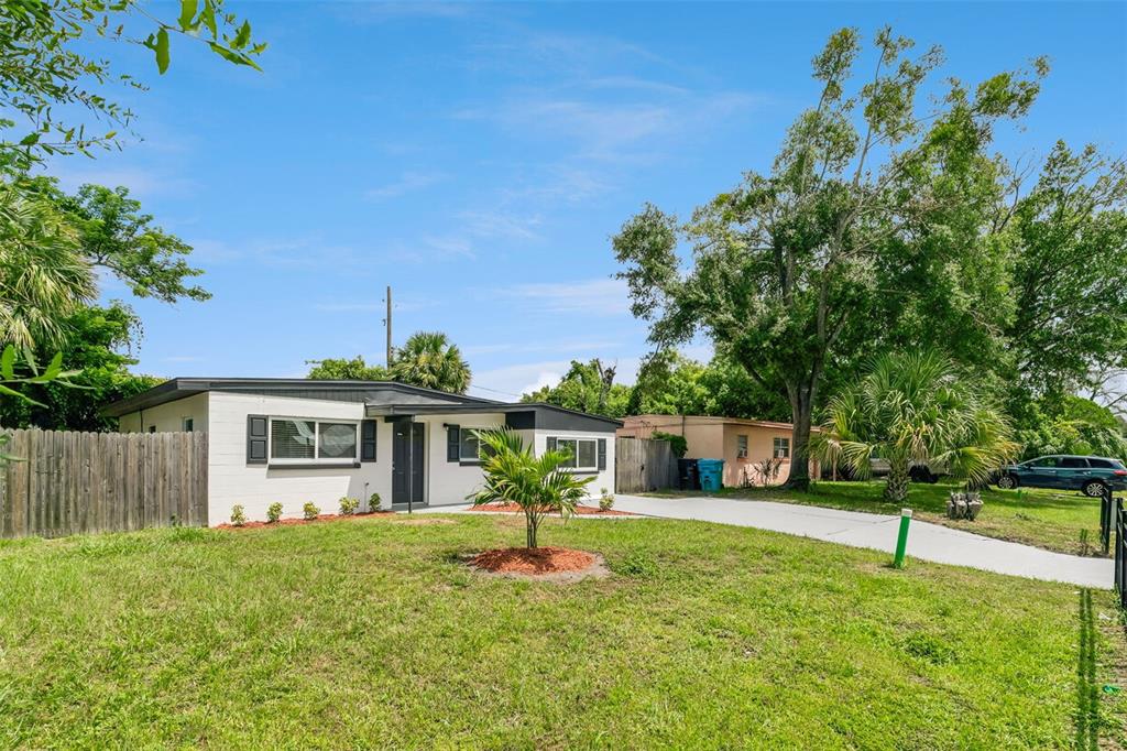 A single-story white house with a flat roof, a concrete driveway, and a wooden fence — 2821 W AMELIA STREET, ORLANDO, FL