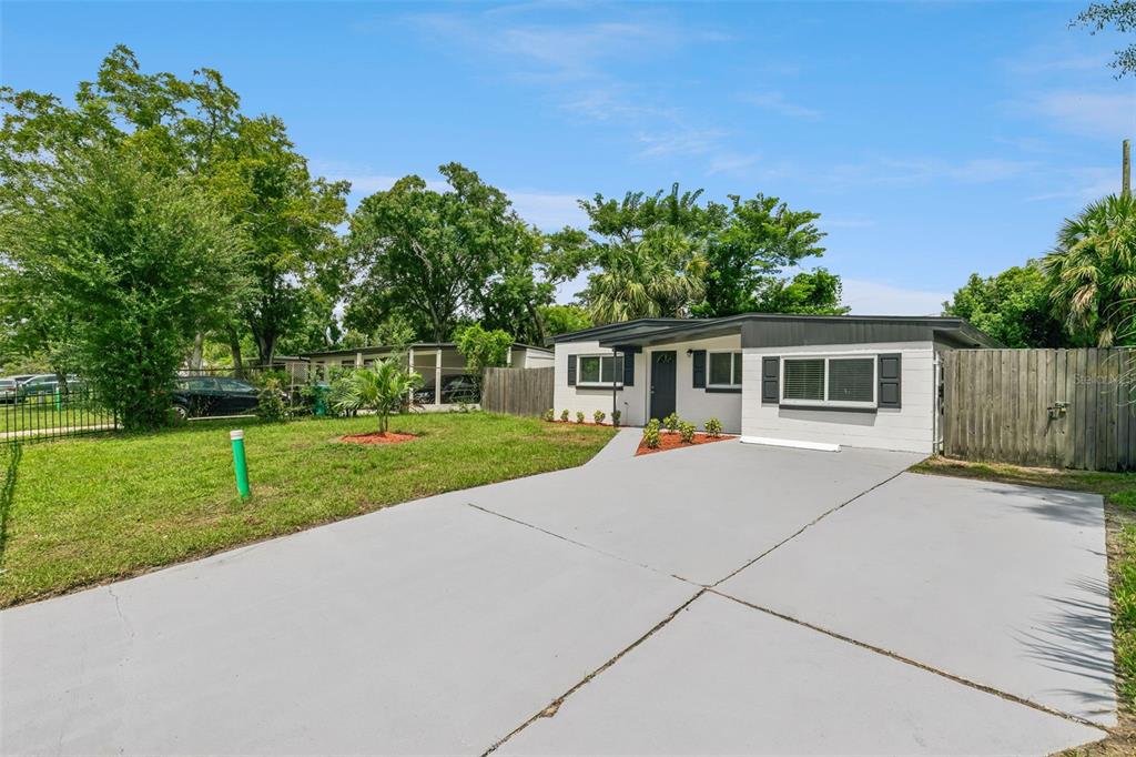 A single-story house with a white exterior, a gray driveway, and a wooden fence — 2821 W AMELIA STREET, ORLANDO, FL