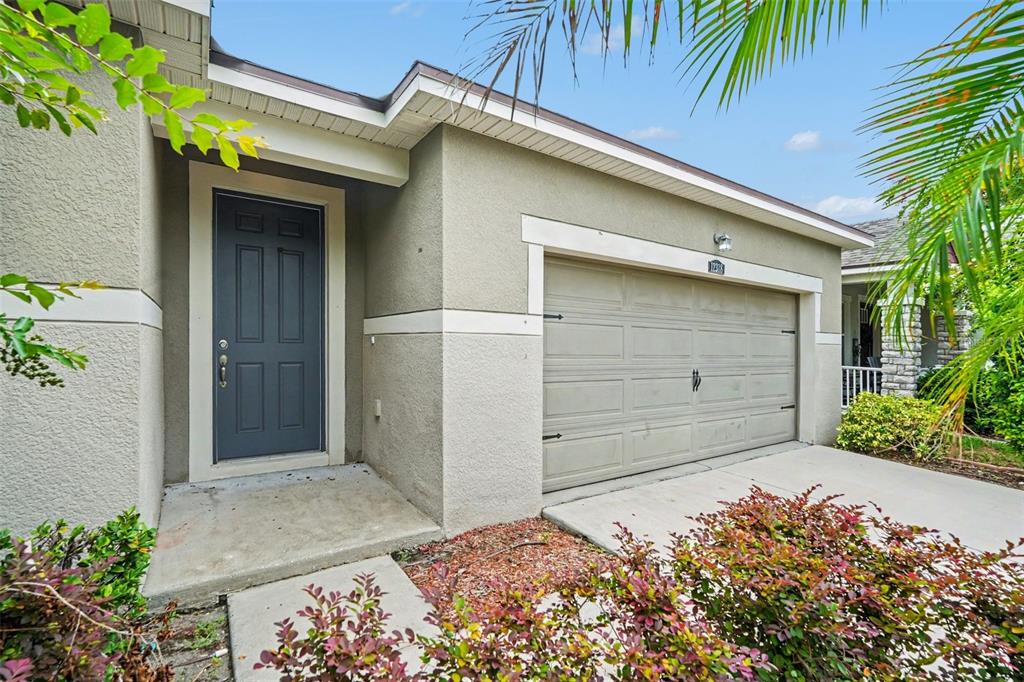 A tan stucco house exterior features a dark gray front door and a beige garage — 12318 EAGLE SWOOP PLACE, RIVERVIEW, FL