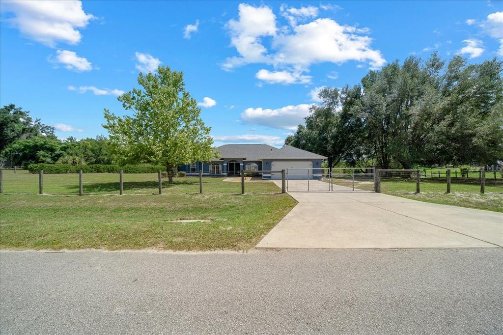 A blue single-story house with a white garage door and a large front yard — 11985 SE 123RD AVENUE, OCKLAWAHA, FL