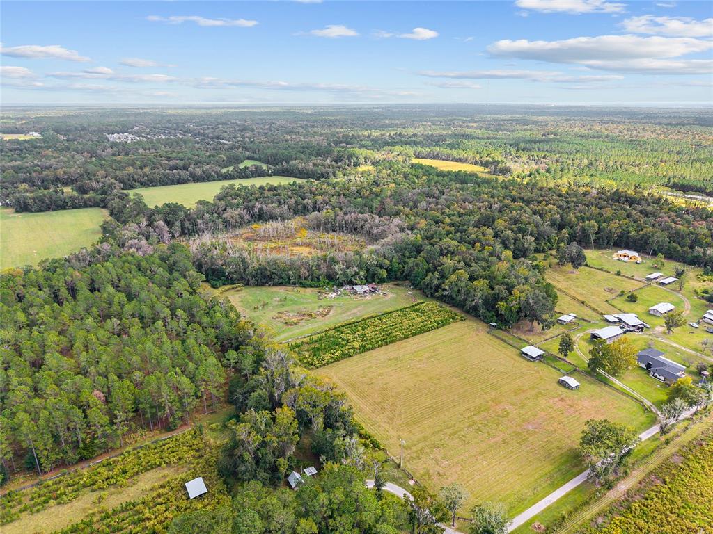 An aerial view shows a large rural property with open fields, forested areas, and outbuildings — 8543 NW 71 TERRACE, GAINESVILLE, FL