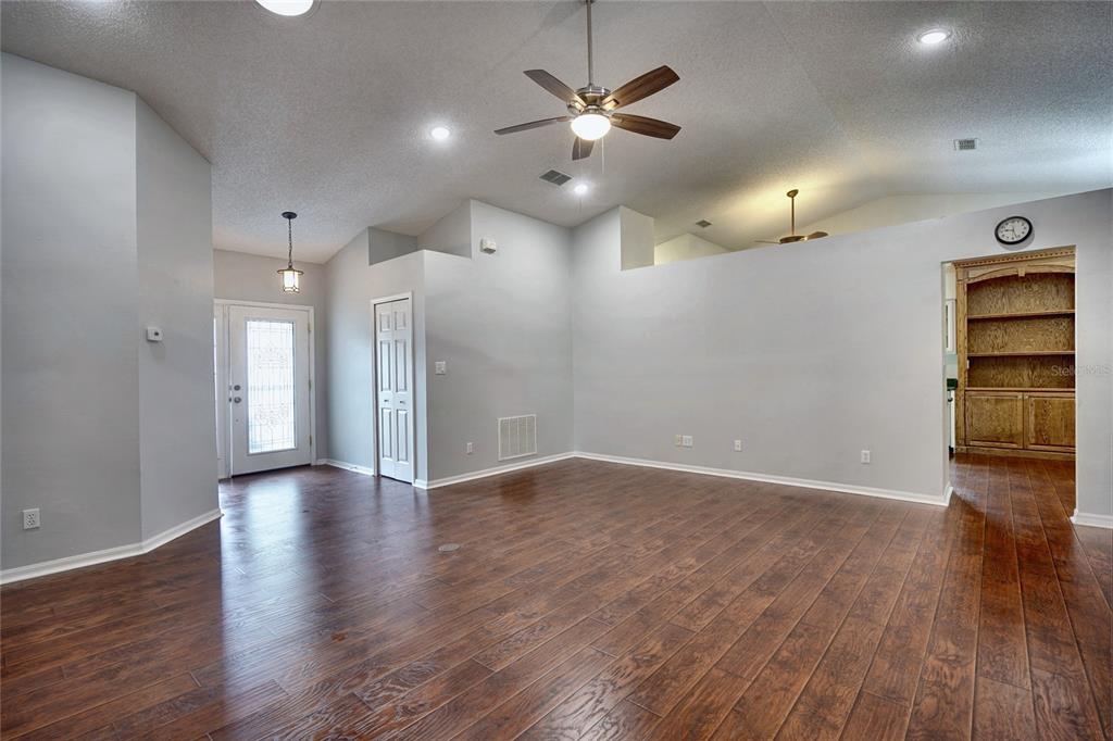 A living room with wood-look flooring, a ceiling fan, and a built-in wooden bookshelf — 25735 GLEN EAGLE DRIVE, LEESBURG, FL