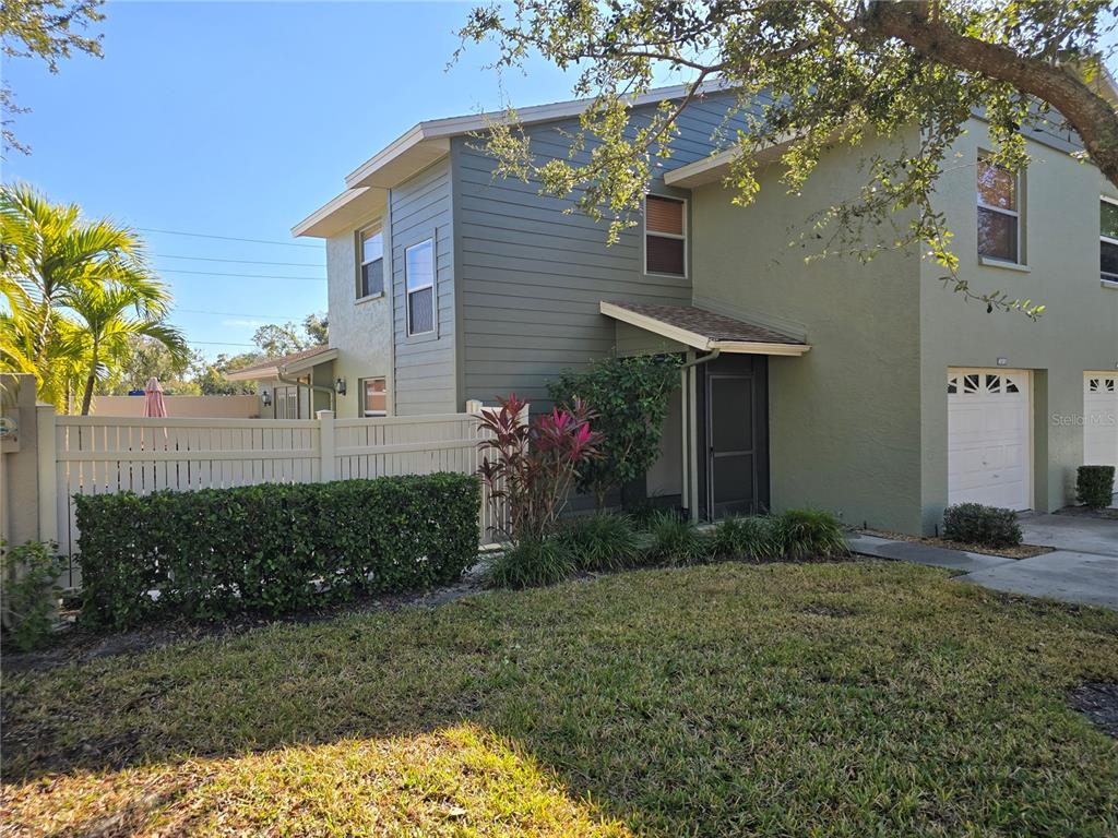 The exterior of a two-story home features green siding, a stone walkway, and a screen door — 4181 CENTER POINTE CIRCLE UNIT 91B, SARASOTA, FL
