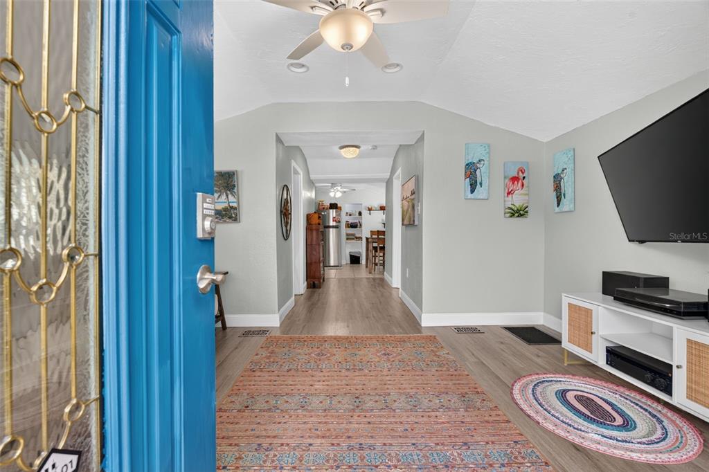 An entryway leads into a living area with light wood floors, a rug, and television — 5161 RENA STREET N, ST PETERSBURG, FL