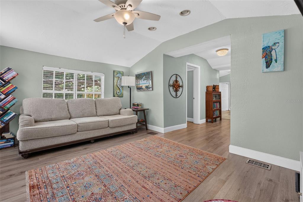A living room features a beige sofa, a patterned area rug, and light-colored wood flooring — 5161 RENA STREET N, ST PETERSBURG, FL