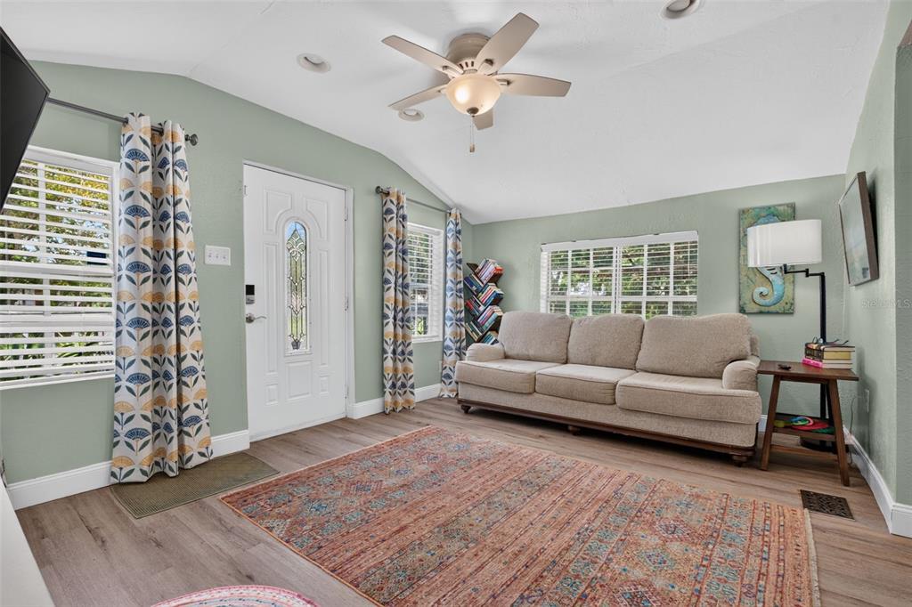 A living room with light green walls, a beige sofa, patterned curtains, and a patterned rug — 5161 RENA STREET N, ST PETERSBURG, FL