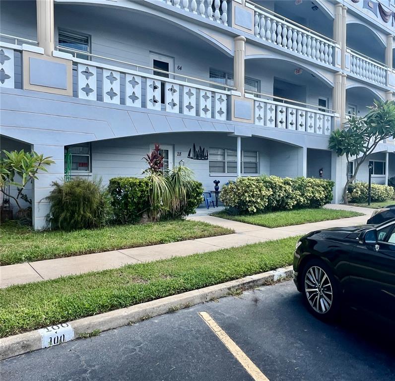 A multi-story apartment building with blue exterior walls, balconies, and a parking space in front — 2460 FRANCISCAN DRIVE UNIT 28, CLEARWATER, FL