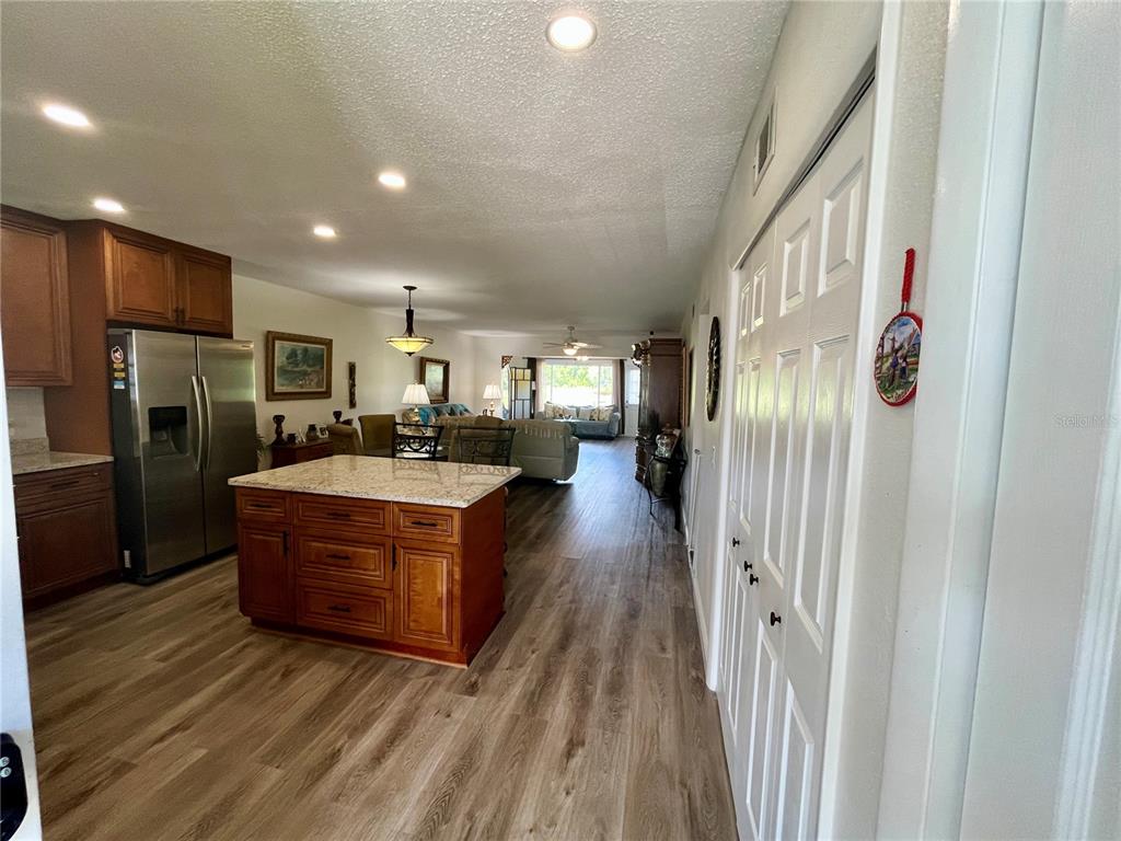 A kitchen with a granite-topped island and wood cabinets opens into a living area — 2460 FRANCISCAN DRIVE UNIT 28, CLEARWATER, FL