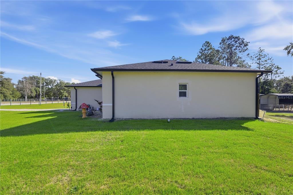 A side view of a beige, single-story house with a dark roof and a small window — 13920 NE 6TH STREET, WILLISTON, FL