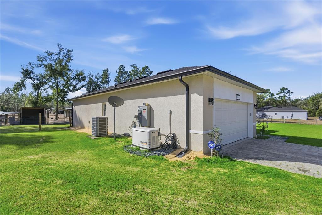 The exterior side of a house features a garage, a generator, and an HVAC unit — 13920 NE 6TH STREET, WILLISTON, FL