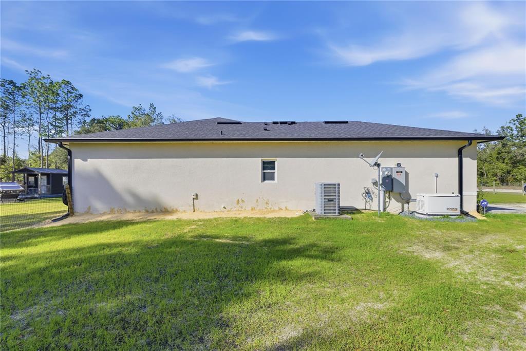 The exterior view shows the side of a house with a generator and HVAC unit — 13920 NE 6TH STREET, WILLISTON, FL