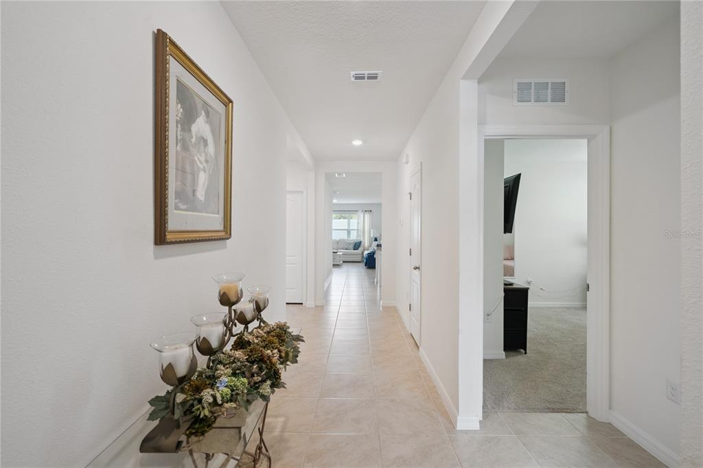 A tiled hallway features a framed picture, a decorative candle centerpiece, and an open doorway — 2073 SWANSON DRIVE, DELTONA, FL