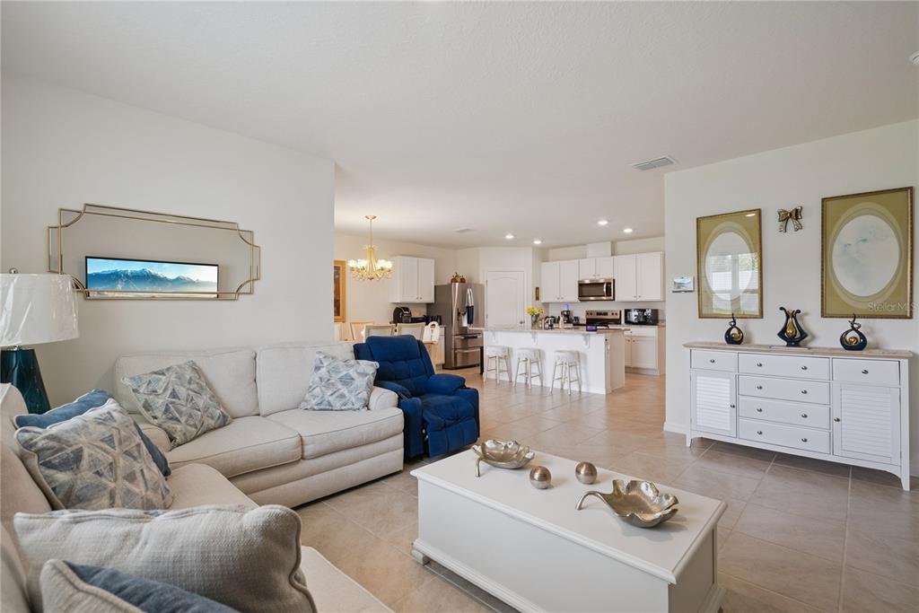 A living room with a white sofa and blue recliner opens into a kitchen with island — 2073 SWANSON DRIVE, DELTONA, FL