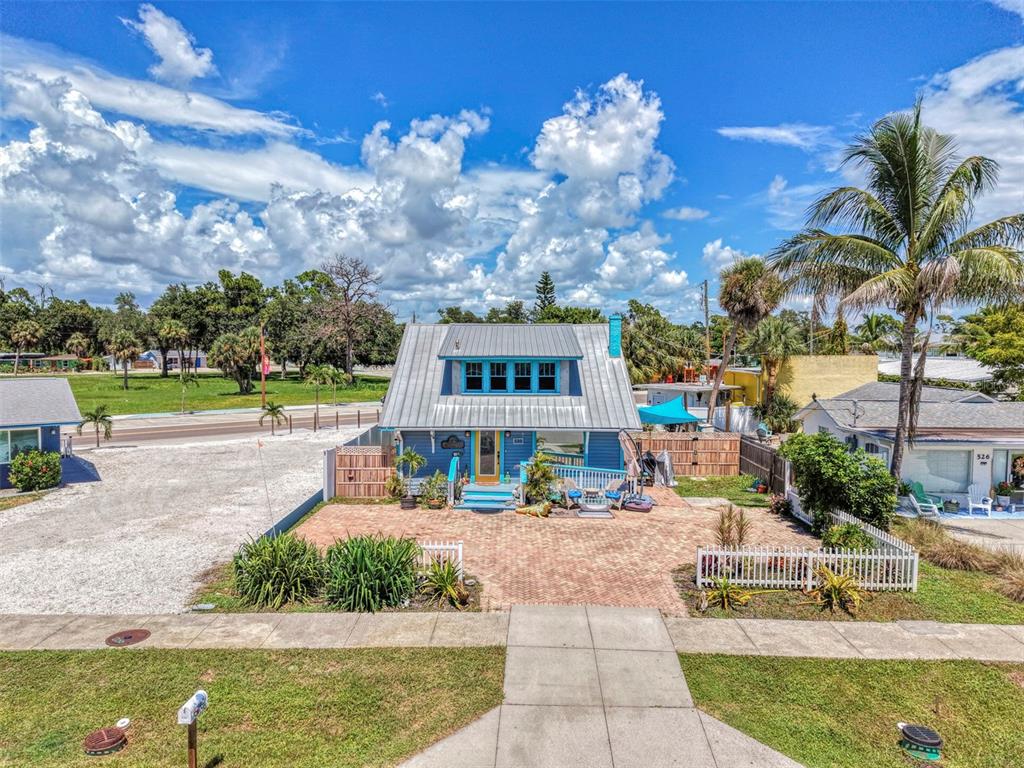 A blue two-story house with a metal roof sits behind a brick-paved front yard — 530 W GREEN STREET, ENGLEWOOD, FL