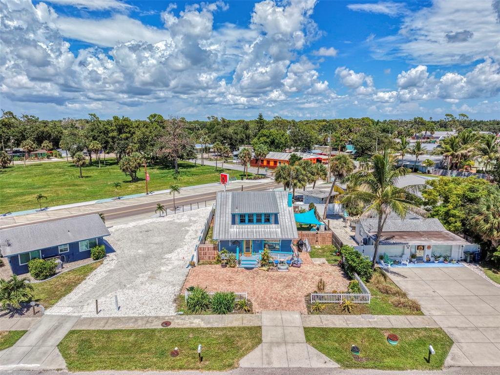 An aerial view shows a blue house with a metal roof and a brick driveway — 530 W GREEN STREET, ENGLEWOOD, FL