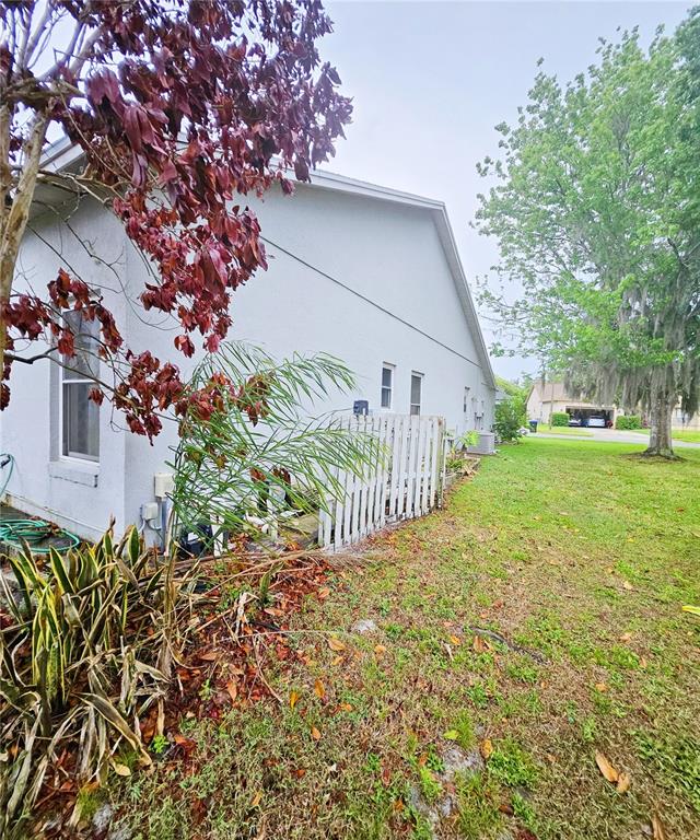 The exterior side of a light-colored house features a white fence and landscaping — 14601 POTANOW TRAIL, ORLANDO, FL