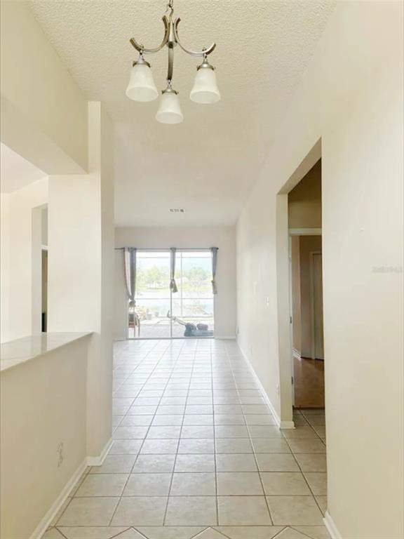 A tiled hallway leads to a living area with sliding glass doors and a chandelier — 14601 POTANOW TRAIL, ORLANDO, FL