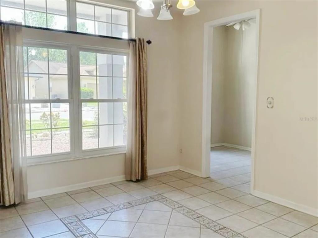 A dining room with tile flooring, large windows, beige walls, and a chandelier — 14601 POTANOW TRAIL, ORLANDO, FL