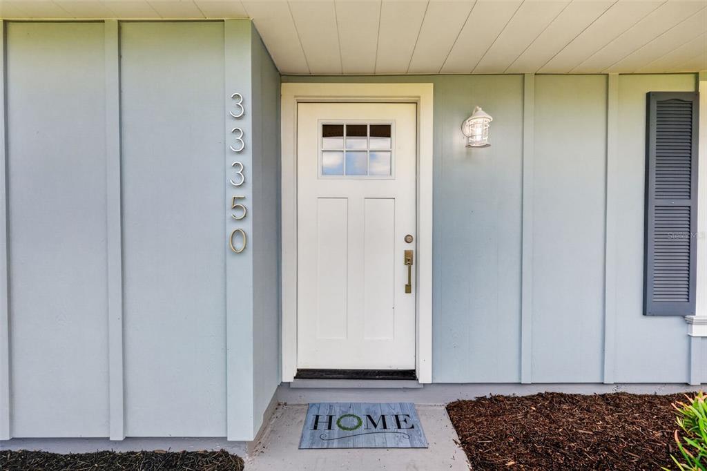 A white front door with a window sits on a light blue house exterior — 33350 E LAKE JOANNA DRIVE, EUSTIS, FL