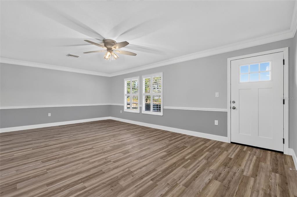 An empty room with gray two-tone walls, wood-look flooring, a ceiling fan, and a white door — 33350 E LAKE JOANNA DRIVE, EUSTIS, FL