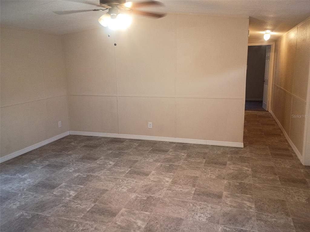 A room with light-colored panel walls, a ceiling fan, and gray tile flooring — 6910 BROOKRIDGE TRAIL, LAKELAND, FL