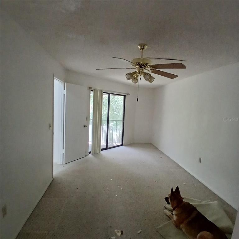 An empty bedroom with beige carpet, a ceiling fan, and a sliding glass door — 9362 NAKOMA WAY, WEEKI WACHEE, FL