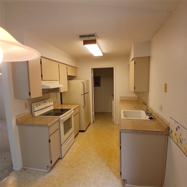 A kitchen features beige cabinets, laminate countertops, a white stove, and a refrigerator — 9362 NAKOMA WAY, WEEKI WACHEE, FL