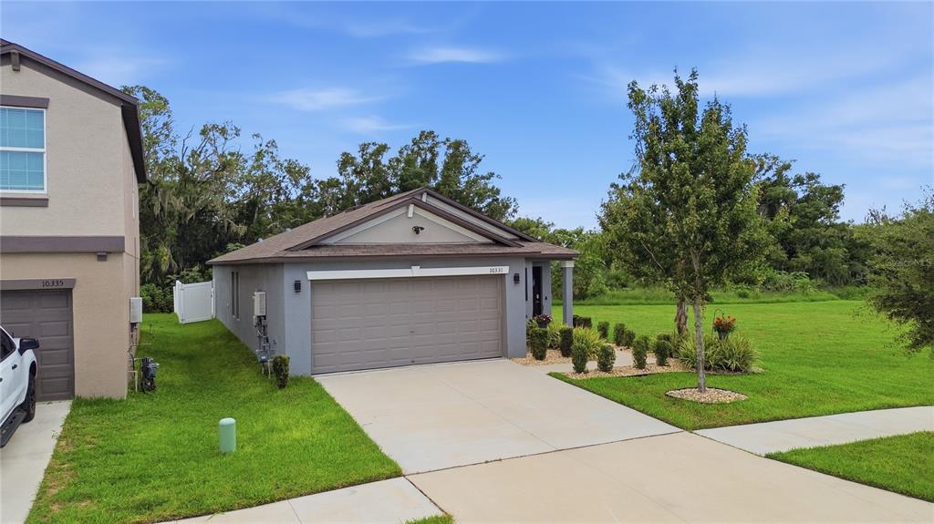 A gray single-story house with a two-car garage and a large side yard — 10331 BLUE PLUME COURT, RIVERVIEW, FL