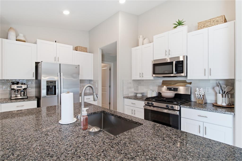 A kitchen features white cabinetry, granite countertops, stainless steel appliances, and a central island — 10331 BLUE PLUME COURT, RIVERVIEW, FL