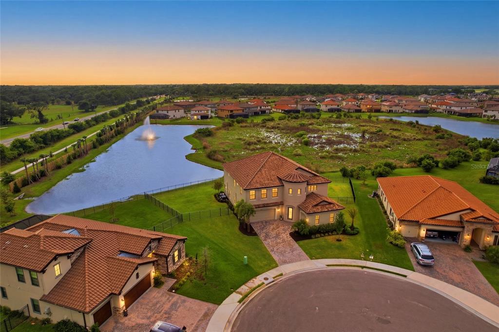 An aerial view shows several suburban houses with tile roofs near a large pond — 8207 RUSHTON PLACE, PARRISH, FL