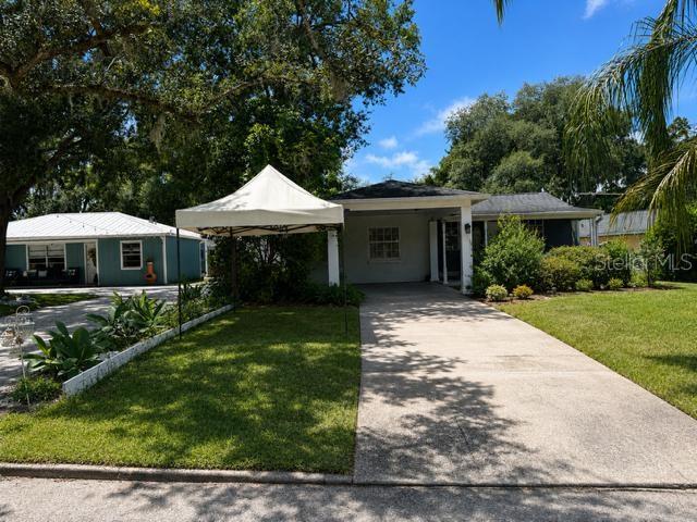 A white pop-up canopy stands on the lawn in front of a single-story house — 11710 NORTH DRIVE, TAMPA, FL