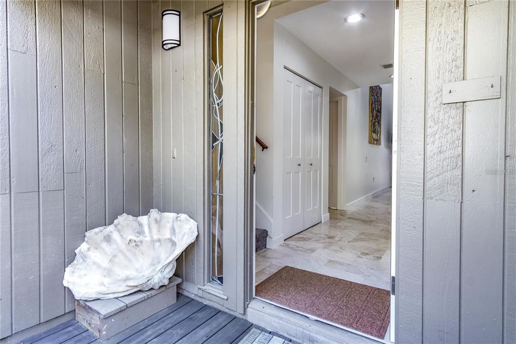 An open front door reveals a tiled entryway with a closet and a hallway inside — 101 WOODLAND PLACE, OSPREY, FL