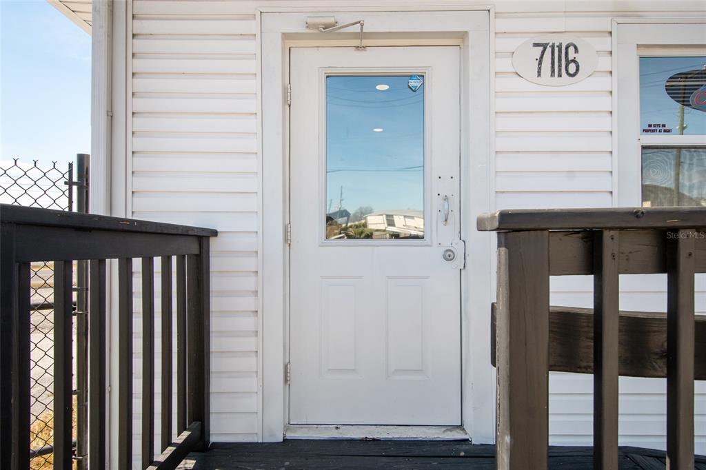 A single-story white building with a ramp and parking lot under a blue sky — 7116 ROSE AVENUE, ORLANDO, FL