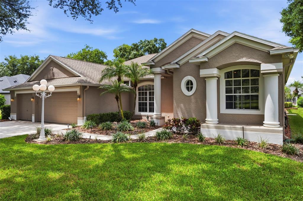A single-story house with a beige stucco exterior, a two-car garage, and white columns — 13756 DOWLING LANE, ODESSA, FL