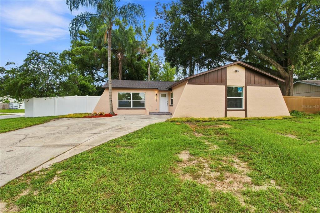 A single-story house with a tan stucco exterior, brown trim, and a concrete driveway — 1105 PARK STREET, SEFFNER, FL